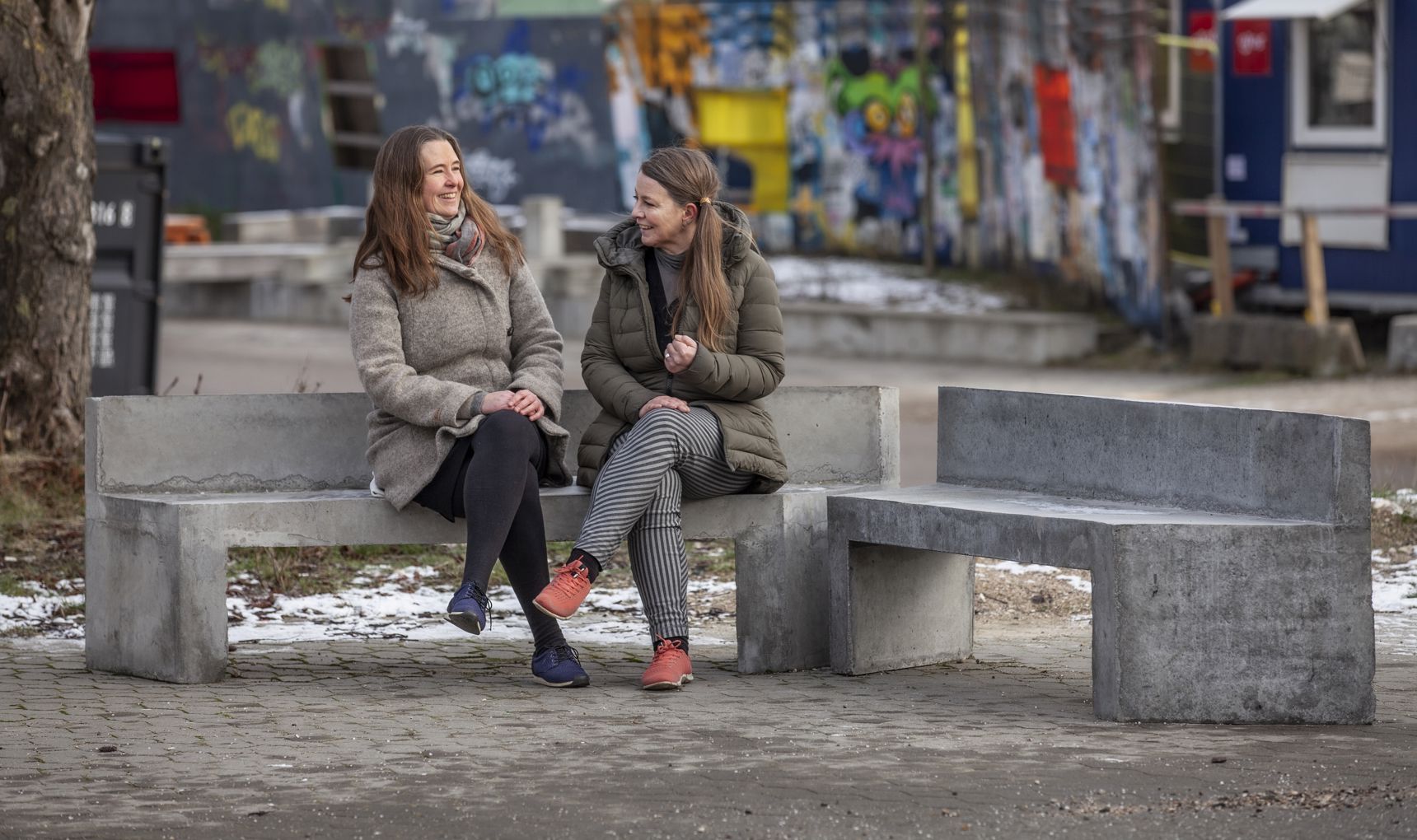 To kvinder sidder på betonbænk