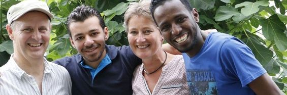 Fire mennesker smiler til kameraet. De har forskellige etniciteter.