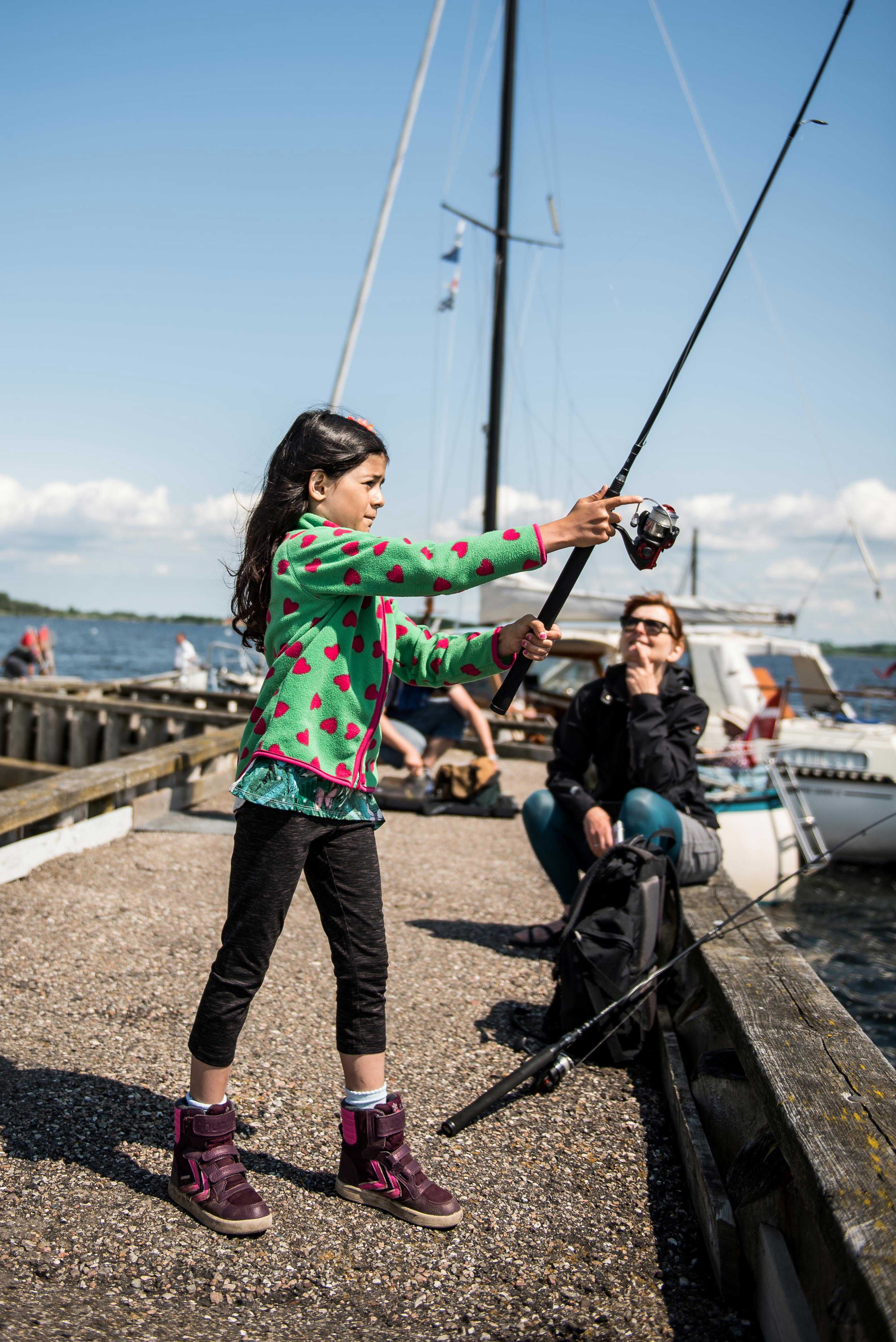 Pige der fisker på mole.