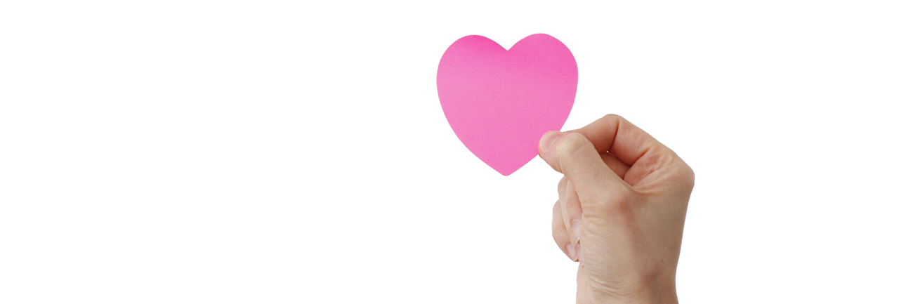 En hånd, der holder et lyserødt papirhjerte mellem tommel- og pegefinger. Baggrunden er helt hvid.