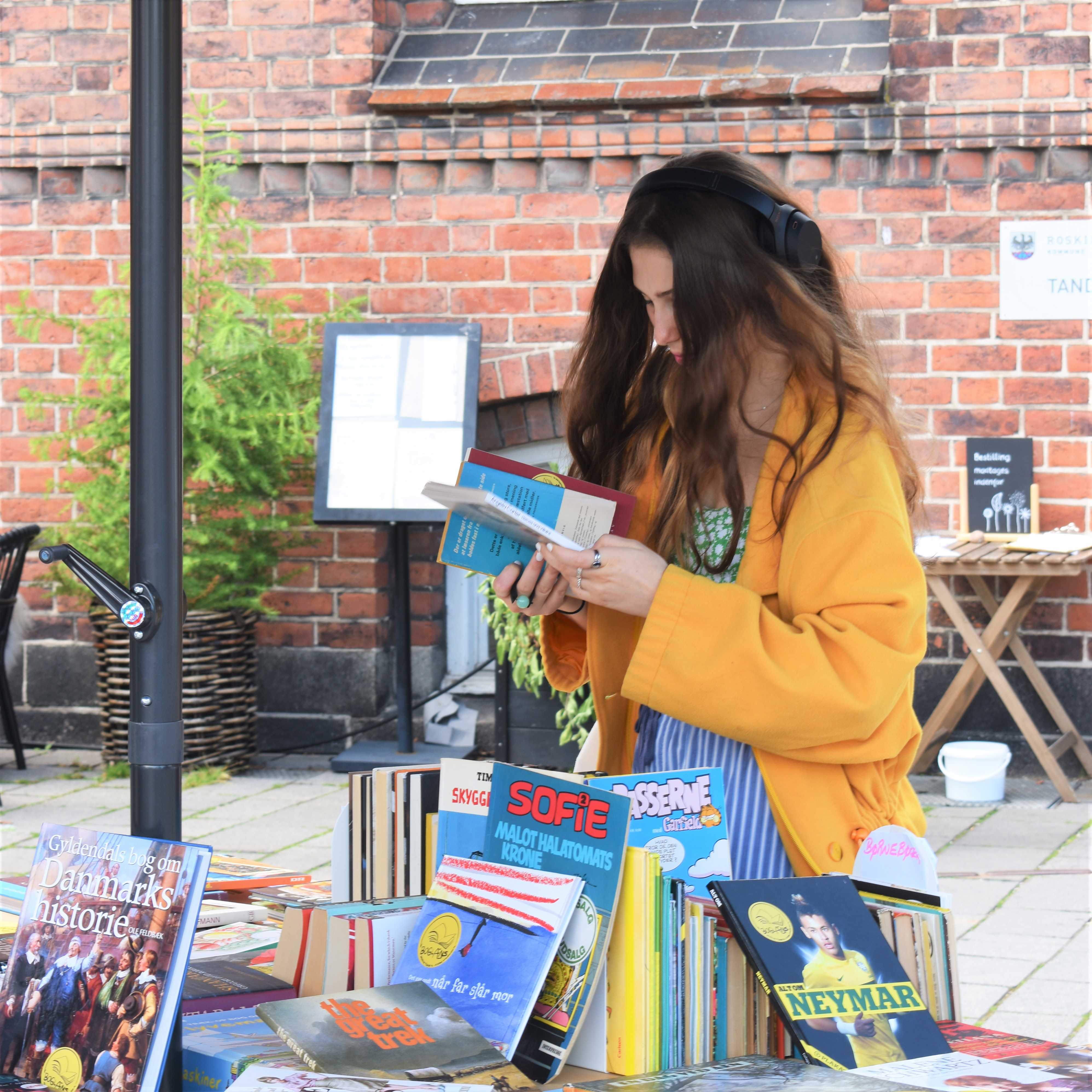 Kvinde i gul jakke kigger på bøger.