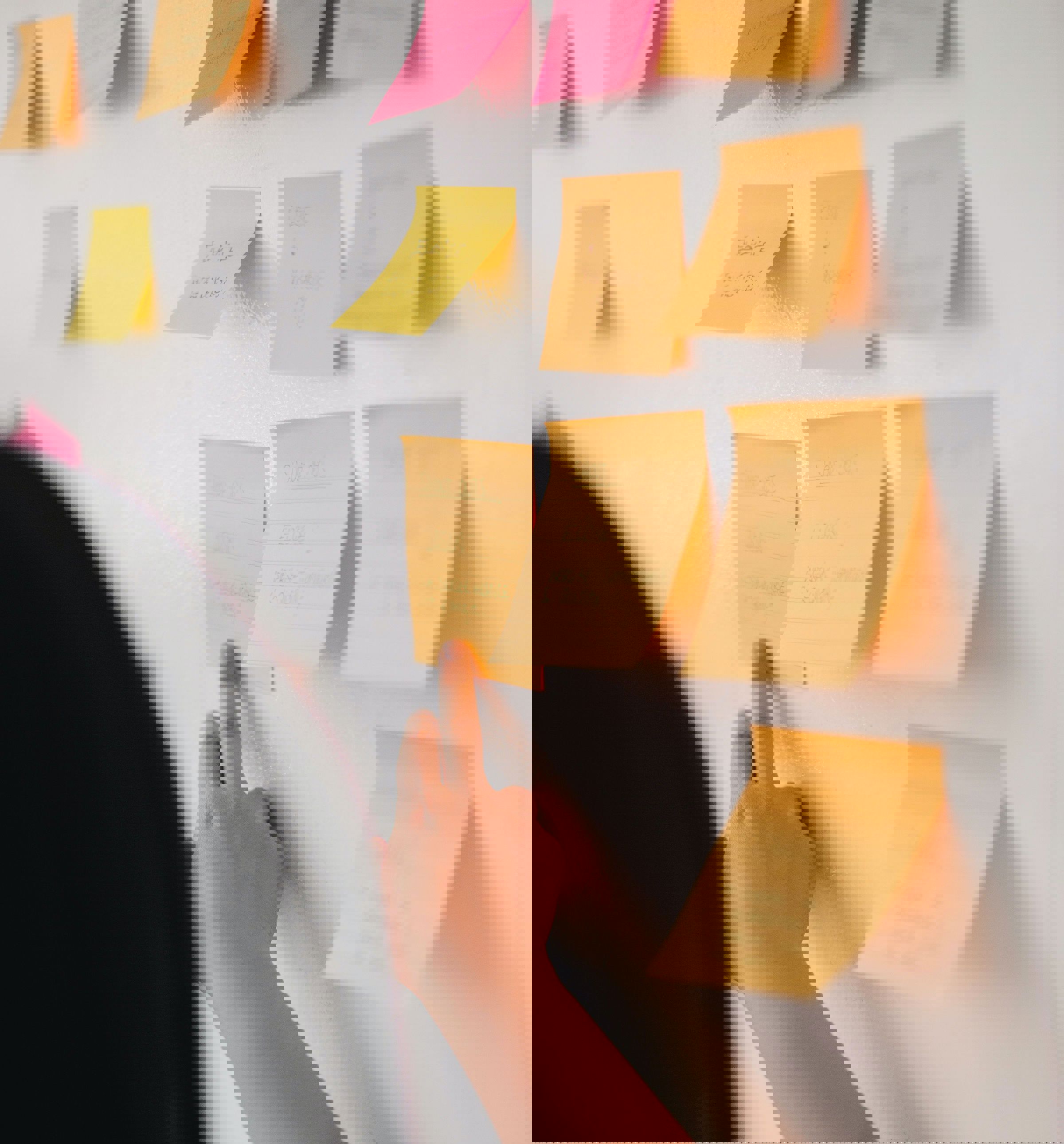 Person, der sætter en note på en væg. Der hænger flere noter på væggen.