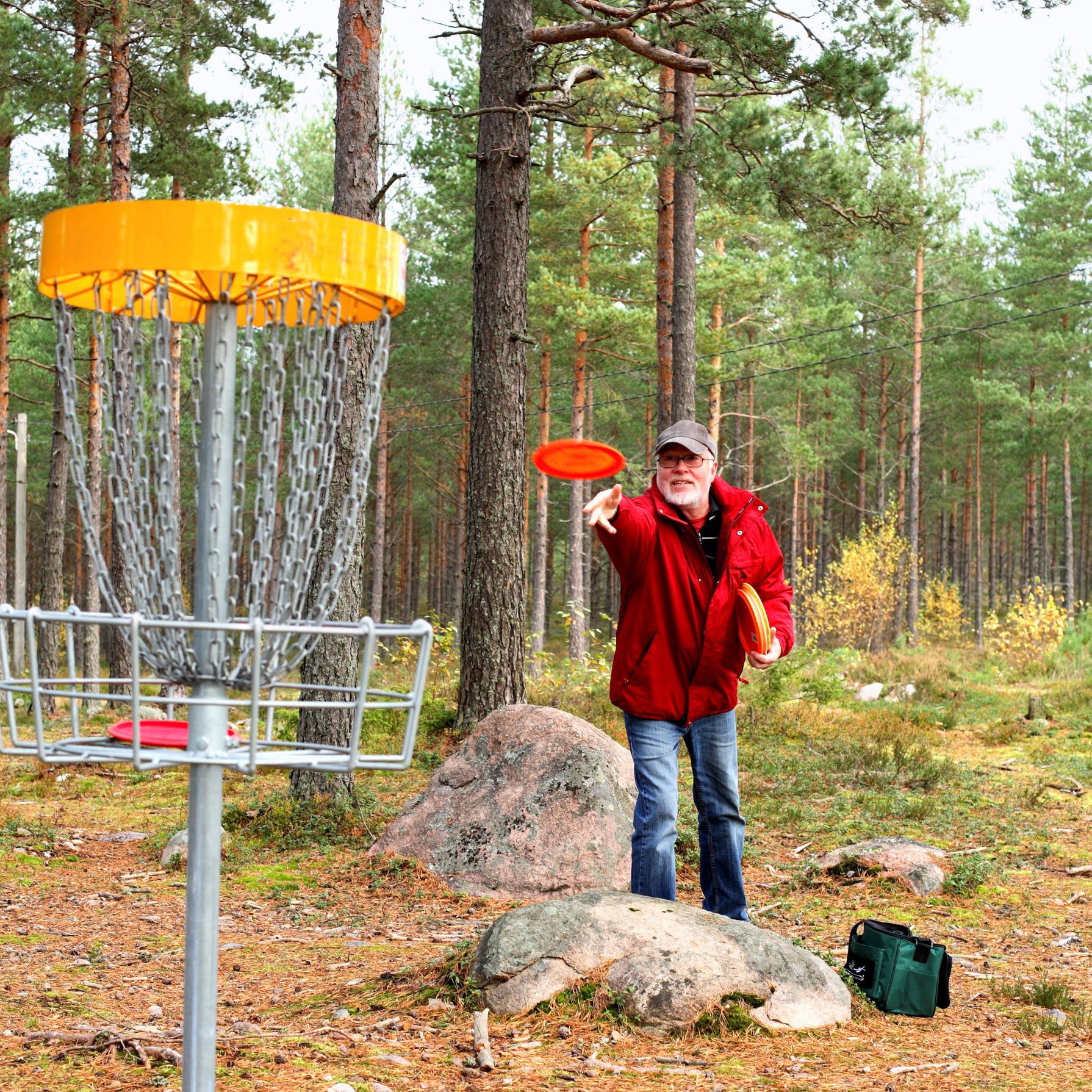 Mand kaster en frisbee. Han spiller discgolf.